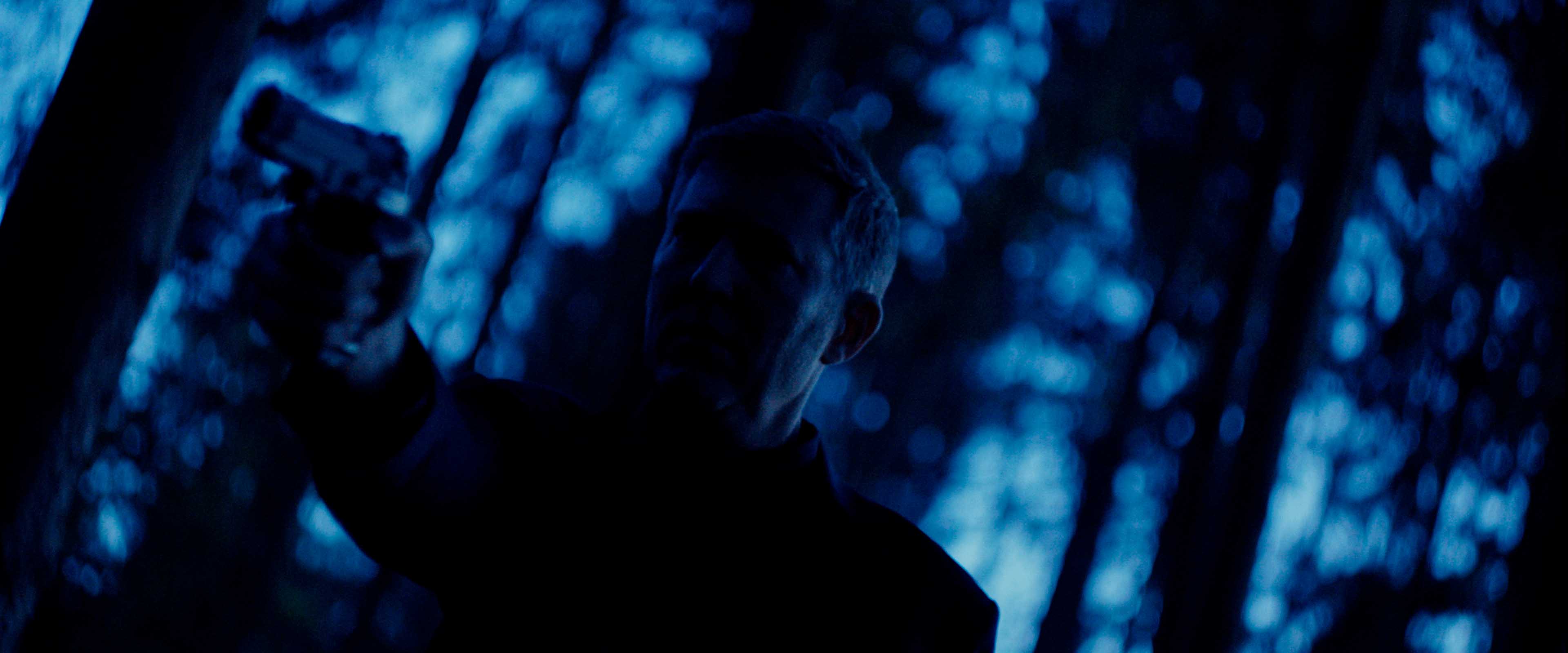 Front-facing Porsche GT3 with headlights on, carving through a chicane at twilight in alpine scenery.