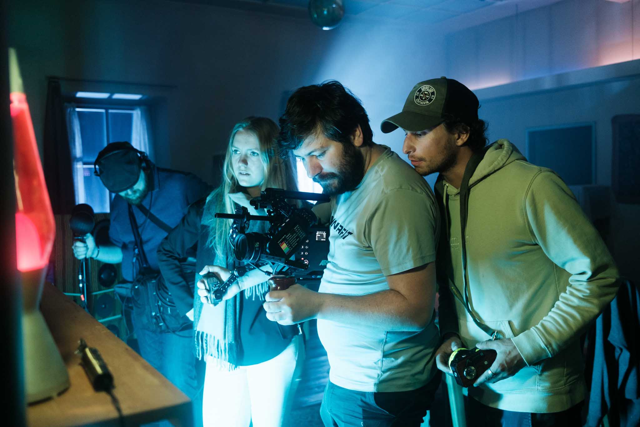 Silhouette of a helmeted racing driver at dusk, mountain skyline faintly visible under violet sky.