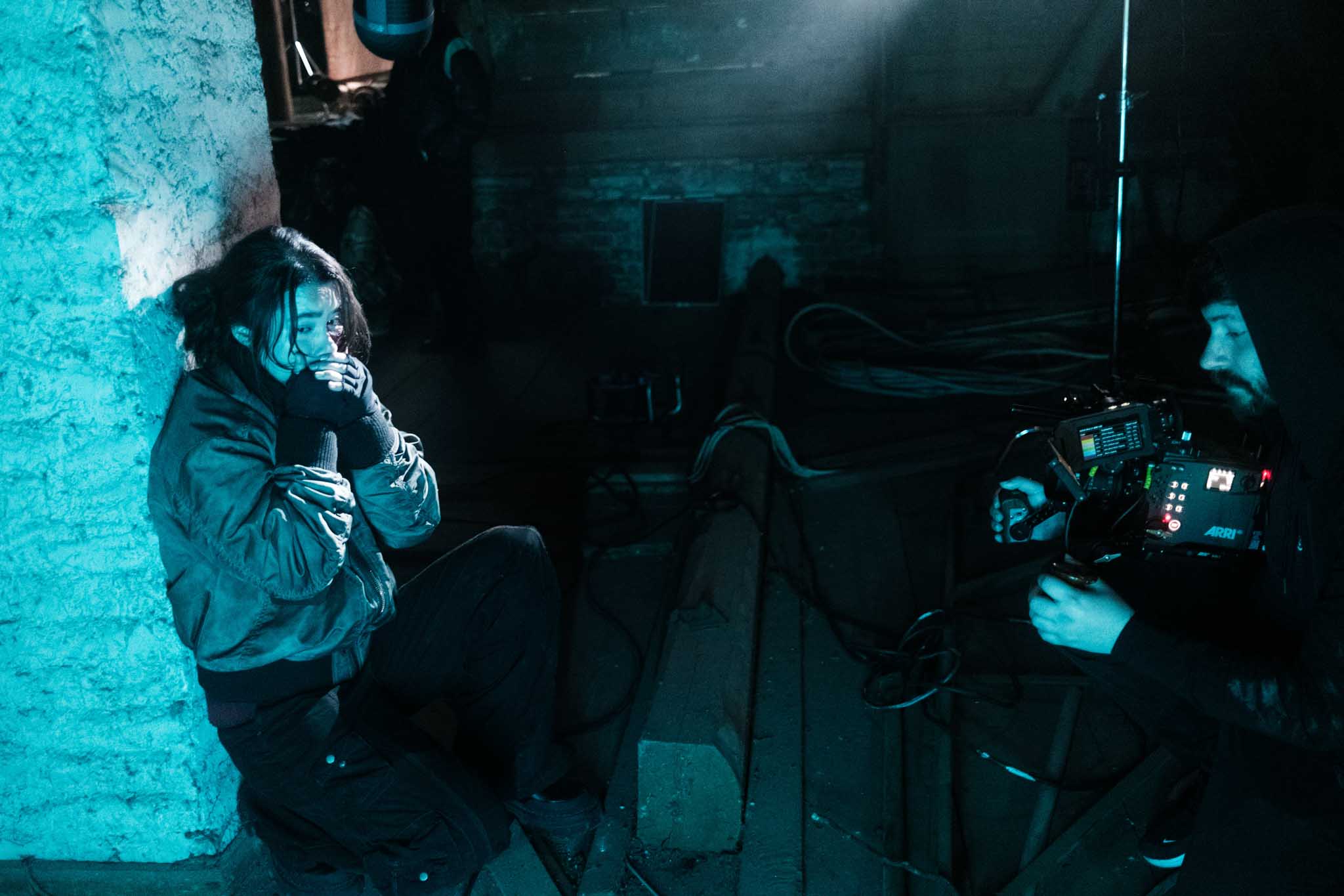 Silhouette of a helmeted racing driver at dusk, mountain skyline faintly visible under violet sky.