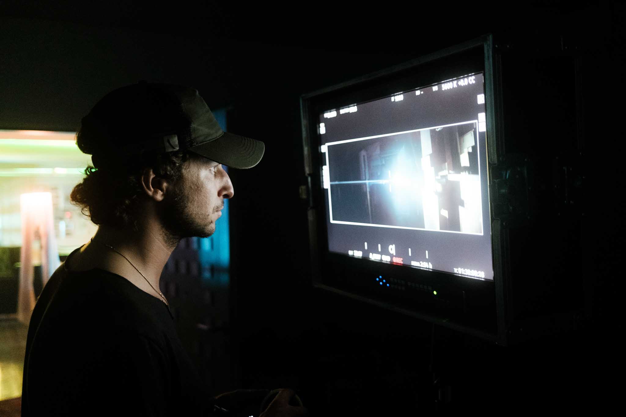 Silhouette of a helmeted racing driver at dusk, mountain skyline faintly visible under violet sky.