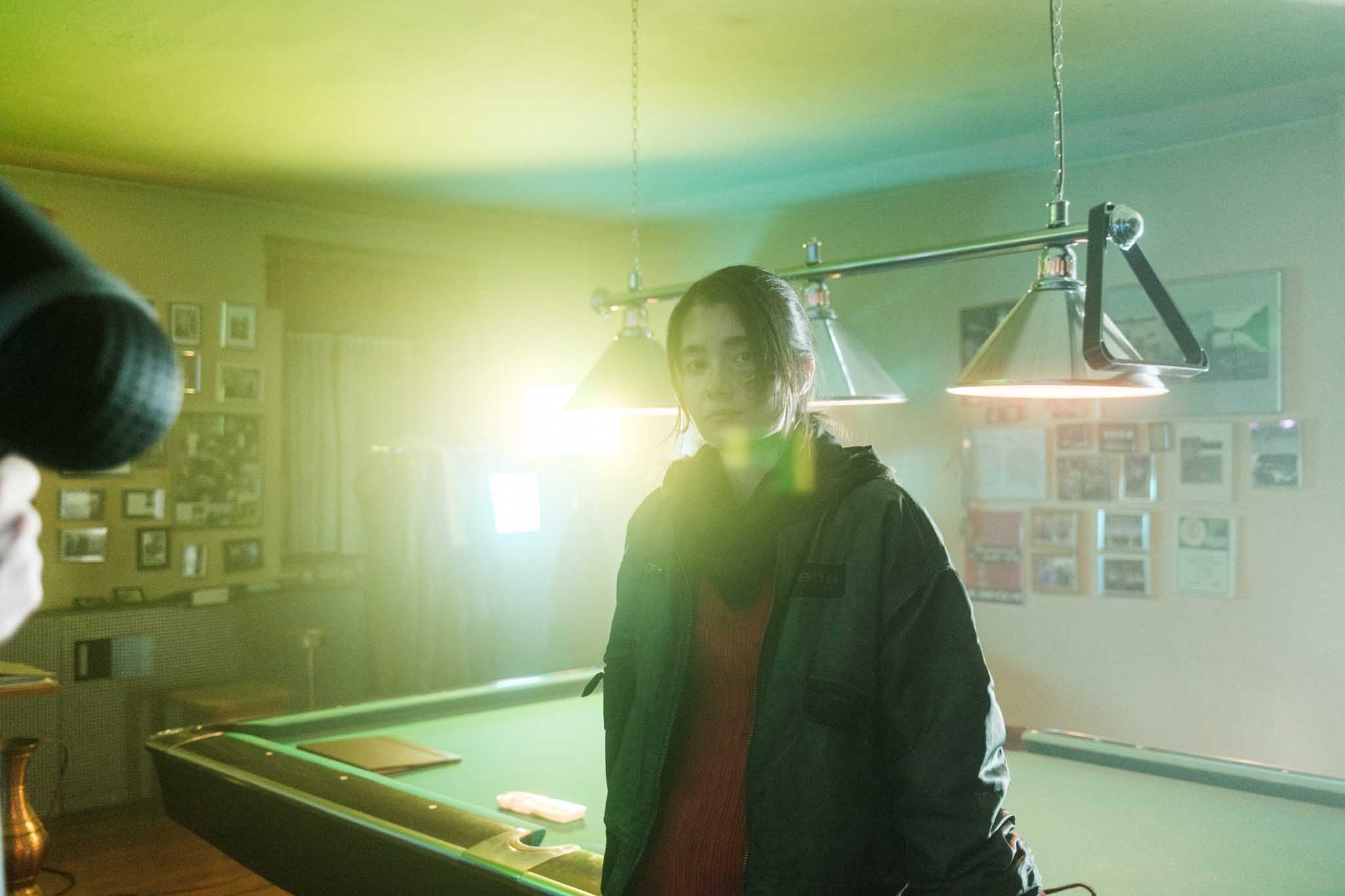 Front-facing Porsche GT3 with headlights on, carving through a chicane at twilight in alpine scenery.