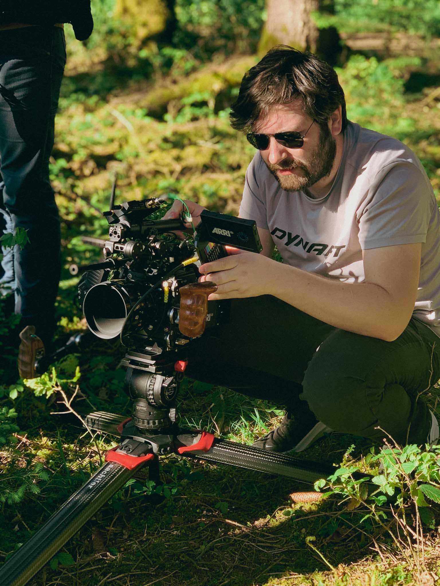 Front-facing Porsche GT3 with headlights on, carving through a chicane at twilight in alpine scenery.