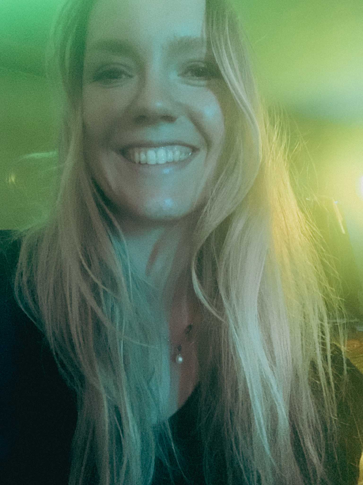 Silhouette of a helmeted racing driver at dusk, mountain skyline faintly visible under violet sky.