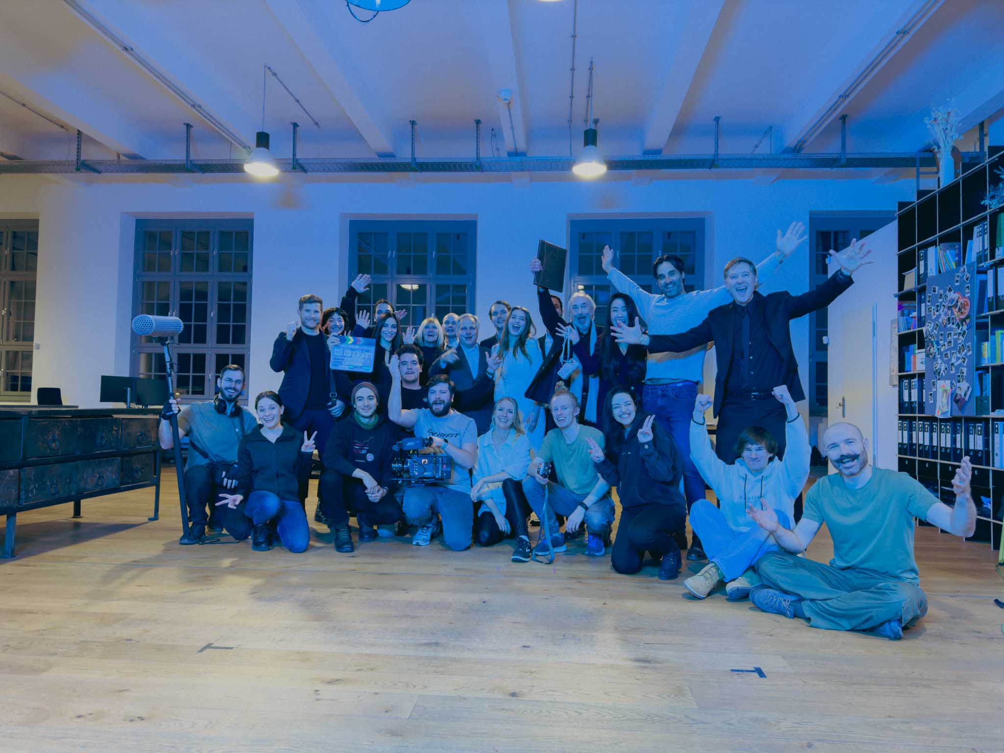 Front-facing Porsche GT3 with headlights on, carving through a chicane at twilight in alpine scenery.