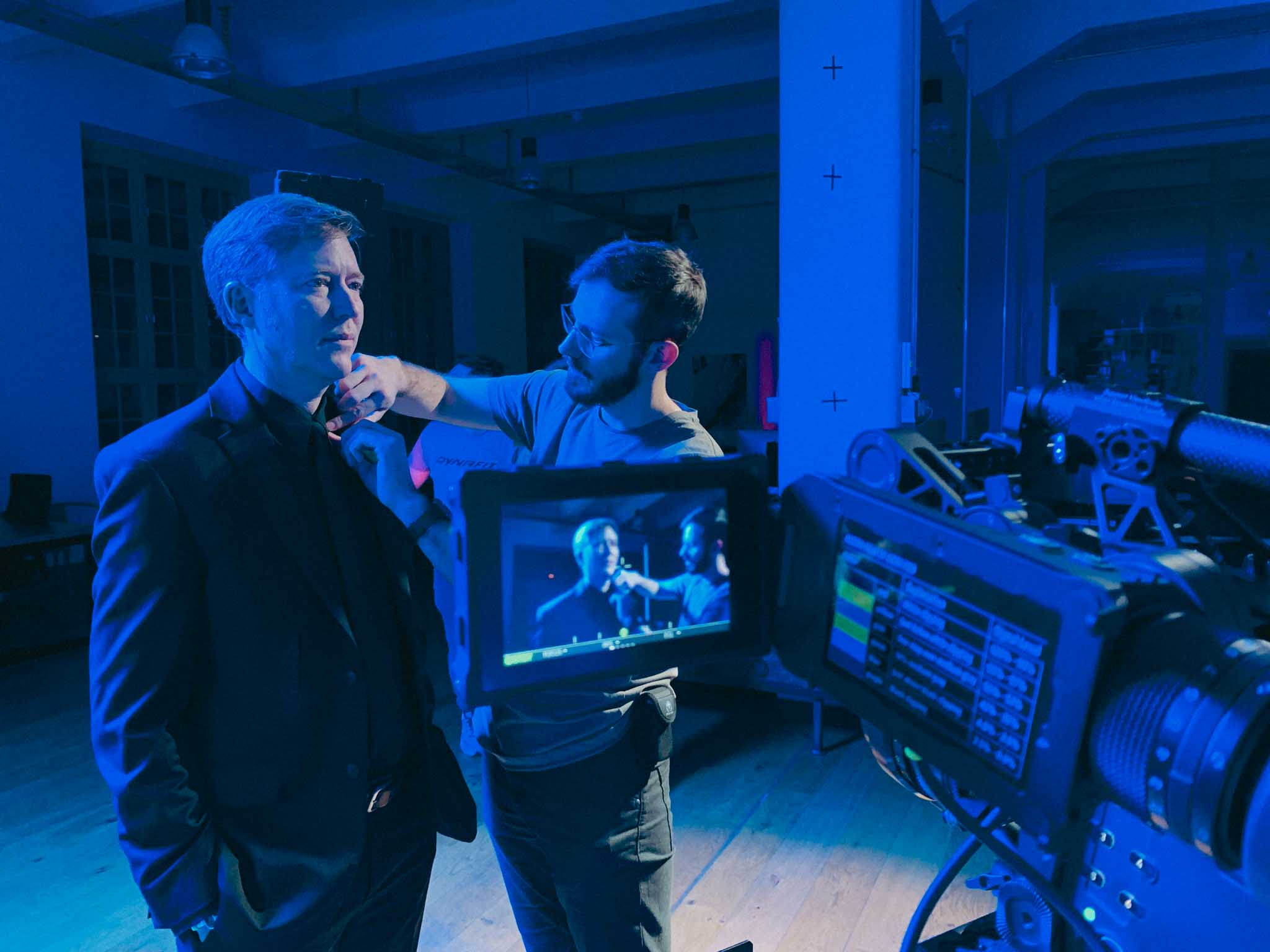 Front-facing Porsche GT3 with headlights on, carving through a chicane at twilight in alpine scenery.