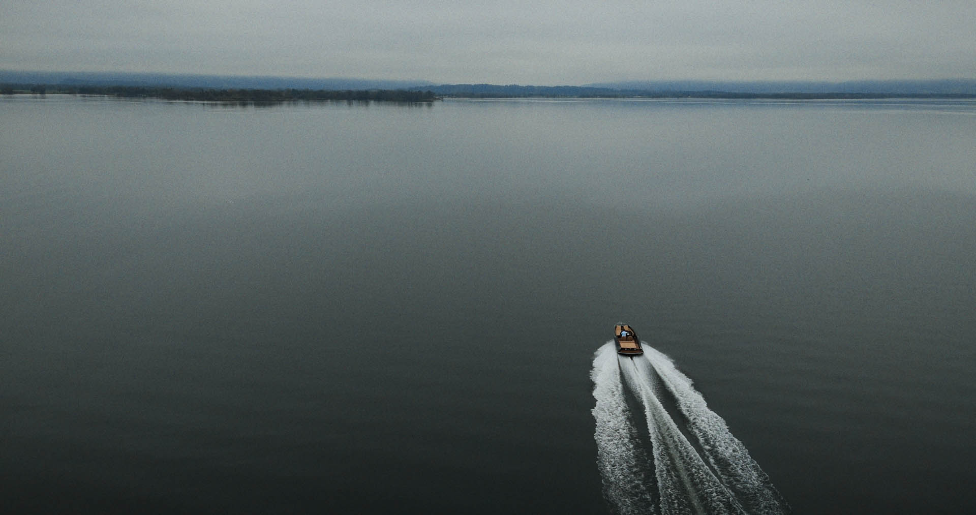 Front-facing Porsche GT3 with headlights on, carving through a chicane at twilight in alpine scenery.