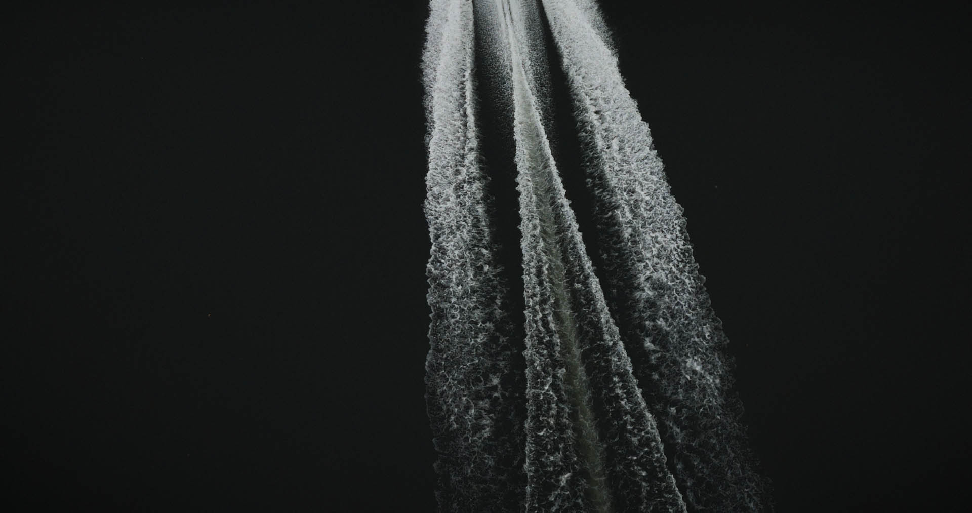 Abstract motion-blur of red and white kerb stripes on dark asphalt, evoking racetrack speed.