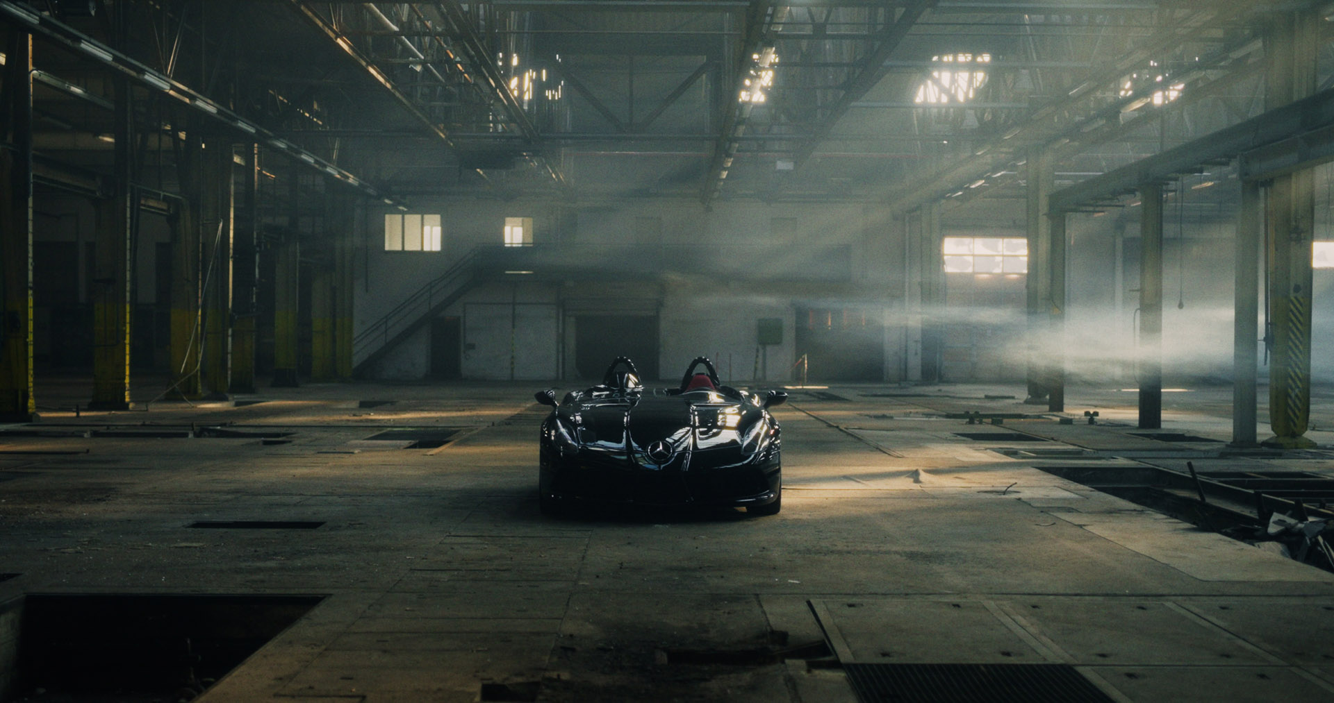 Front-facing Porsche GT3 with headlights on, carving through a chicane at twilight in alpine scenery.
