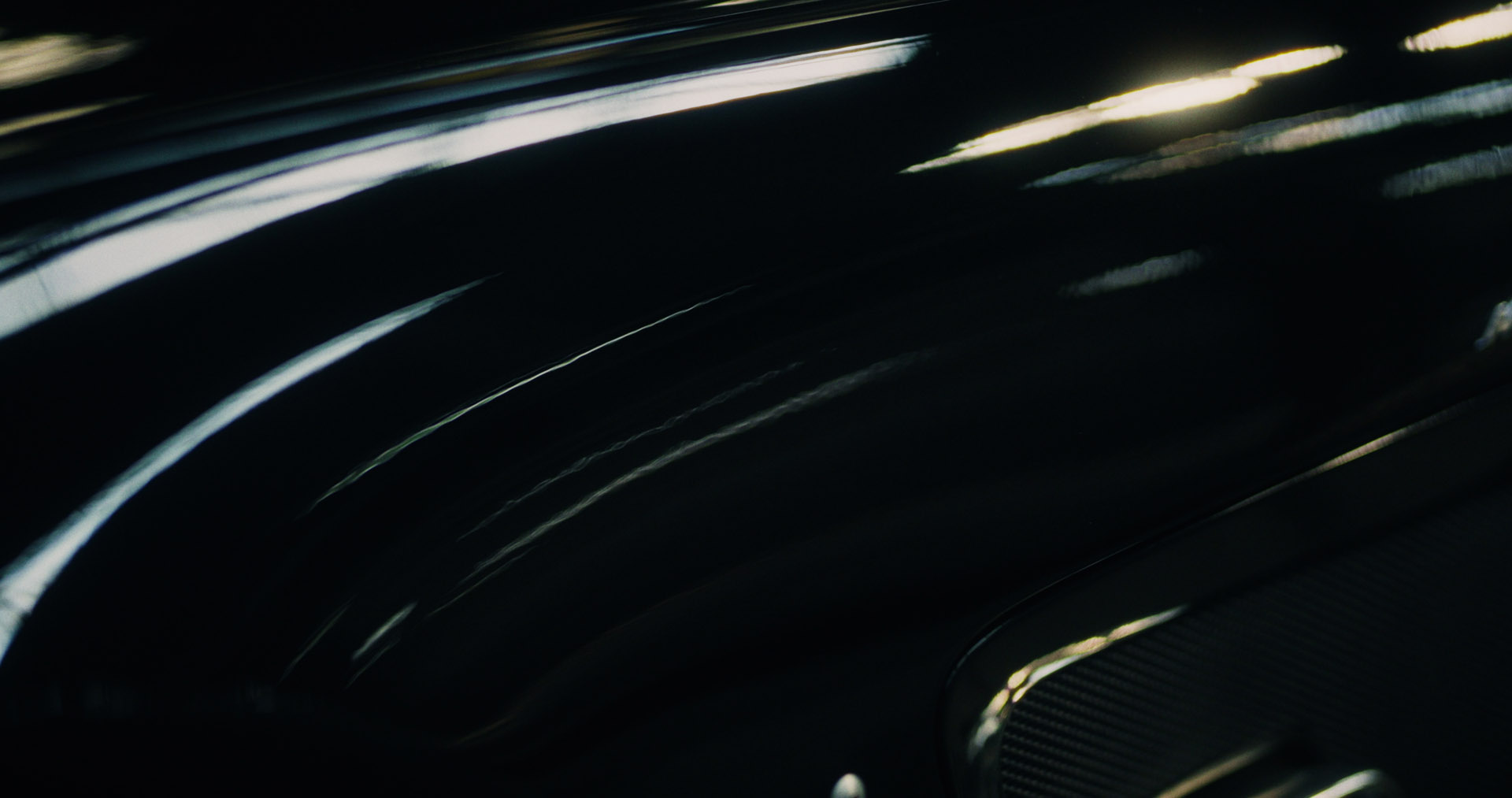Silhouette of a helmeted racing driver at dusk, mountain skyline faintly visible under violet sky.