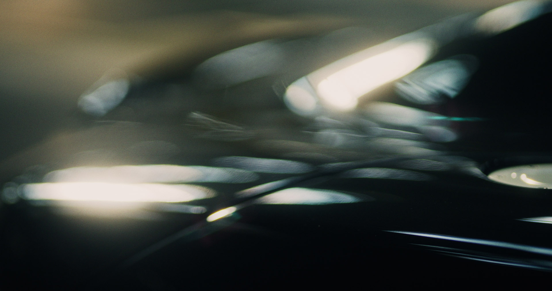Rear view of a Porsche GT3 entering a foggy racetrack curve at dawn, headlights piercing the mist.