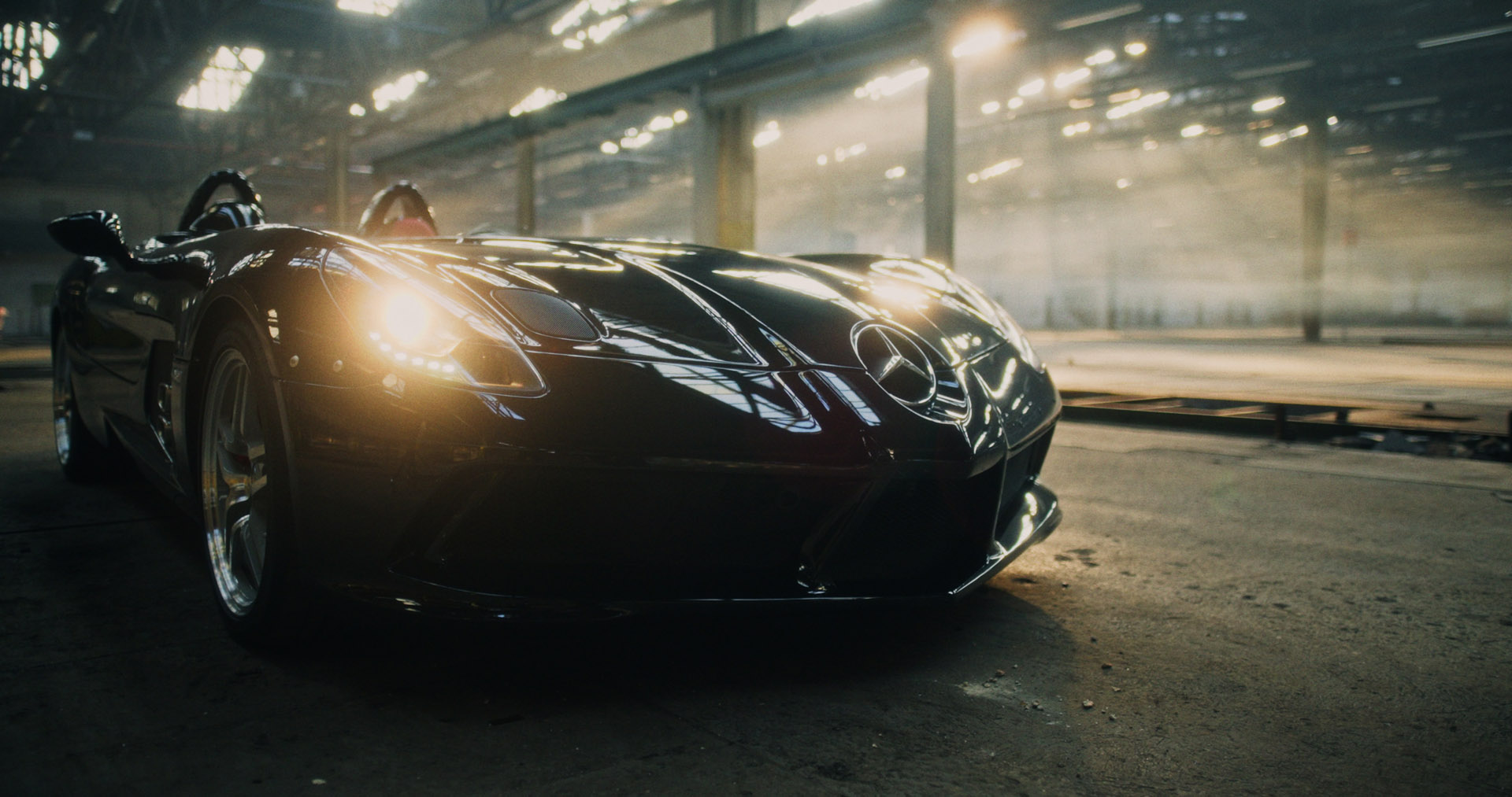 Front-facing Porsche GT3 with headlights on, carving through a chicane at twilight in alpine scenery.